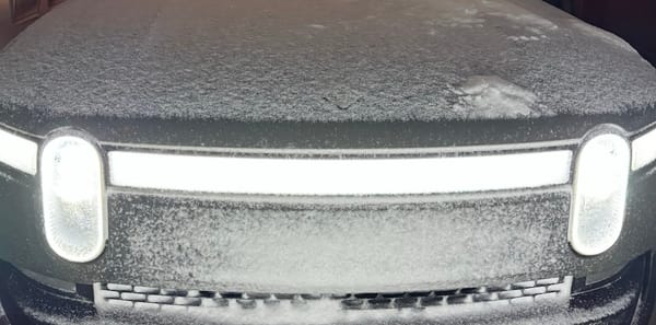 The front of a Rivian R1T with a light dusting of snow.